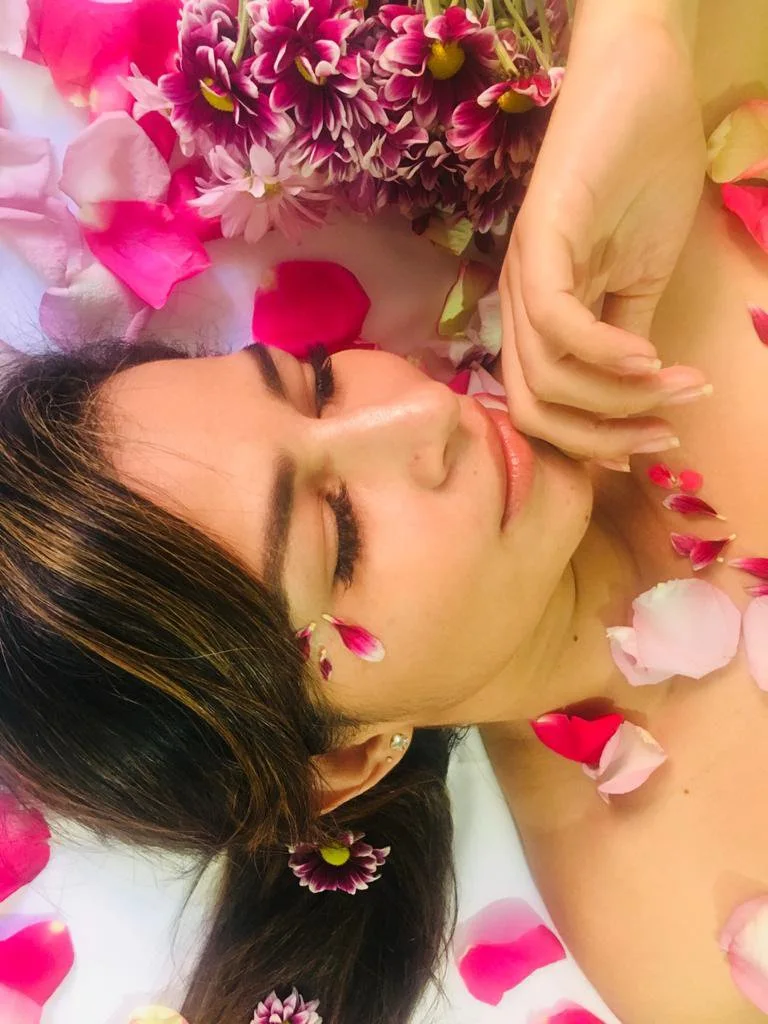 Ritual de uso: mujer con los ojos cerrados entre pétalos de rosa